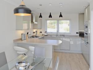 a kitchen with white cabinets and a large white island at Sand Dunes in Tywardreath