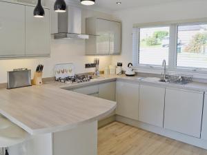 a kitchen with white cabinets and a large island at Sand Dunes in Tywardreath