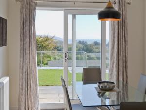 a dining room with a glass table and a large window at Sand Dunes in Tywardreath