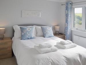 a white bed with towels on it with a window at Sand Dunes in Tywardreath +12 photos