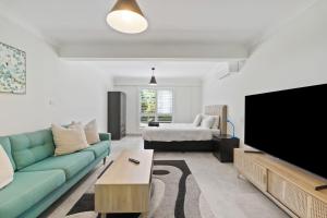 a living room with a couch and a flat screen tv at Fern & Maple Lodge Wentworth Falls in Wentworth Falls