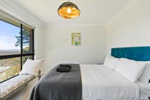 a bedroom with a bed and a large window at Misty Haven at Wentworth Falls in Wentworth Falls