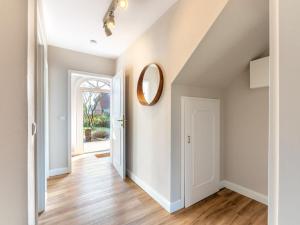 einen Flur mit weißen Wänden, Holzböden und einem Spiegel in der Unterkunft Wening-Hüs in Boldixum
