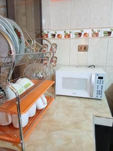 a kitchen with a microwave and a shelf with dishes at Departamento Céntrico in Quillacollo