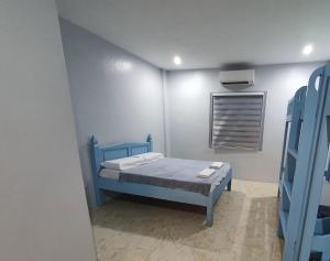 a bedroom with a blue bed and a window at Denzel's Cosy Inn in San Juan +2 photos