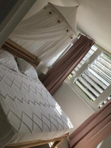 een slaapkamer met een wit bed met een raam bij Grand F2 luxe 3 mn plage avec jardin pointe du bout in Les Trois-Îlets