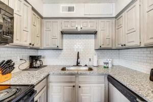 Una cocina con gabinetes blancos y un fregadero. en Upgraded 1BD condo Pool Irving I45, en Sowers