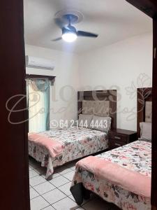 a bedroom with two beds and a ceiling fan at Flores Condominios Casa Narciso in Álamos