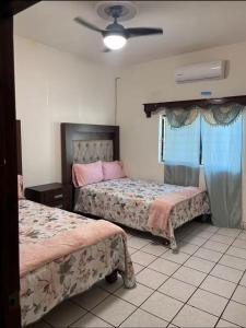 a bedroom with two beds and a ceiling fan at Flores Condominios Casa Narciso in Álamos