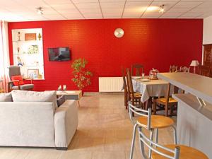 a restaurant with a red wall and tables and a couch at Maison de ferme rénovée avec SPA et salle de jeux - FR-1-489-28 in Cressanges