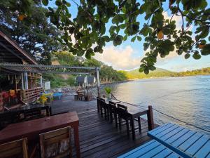 a wooden deck with chairs and tables on the water at Pele's Place Coral Reef Bungalows & Café Maman in Sabang