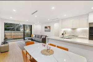 a kitchen and living room with a table and a couch at BoxHill North Designer Grad Home in Box Hill