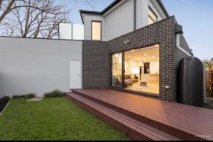 a brick house with a wooden deck in a yard at BoxHill North Designer Grad Home in Box Hill