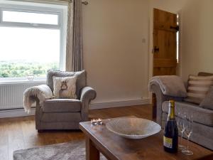 a living room with two chairs and a table with a bottle of wine at Ling Farm Cottage in Holmewood +20 photos