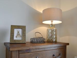 a lamp on top of a dresser with a picture at Ling Farm Cottage in Holmewood