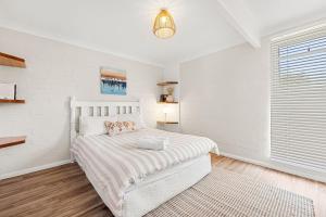 a white bedroom with a bed and a window at Shelleys - Pet Friendly - Short Walk to Beach in Orient Point