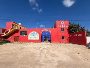 a red building with a blue door in the dirt at Hotel Chuburna in Chuburná
