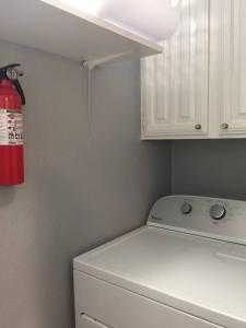 Un extintor rojo cuelga sobre una lavadora. en 1BD Condo Pool South Irving I40, en Sowers