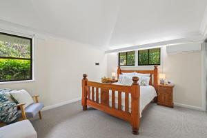 a bedroom with a wooden bed and two windows at Tamborine Mountain Lodge in Mount Tamborine