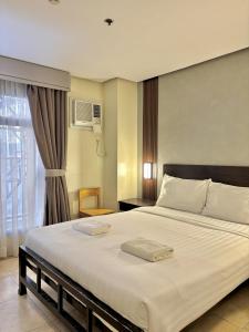 a bedroom with a large white bed with a window at kasa Boutique Hotel Capitol in Cebu City
