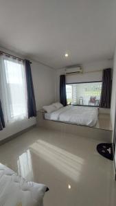 a bedroom with a large bed and two windows at Bukettree homestay satun in Ban Khok