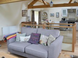 a living room with a couch and a kitchen at Brow View Cottage in Ravenstonedale