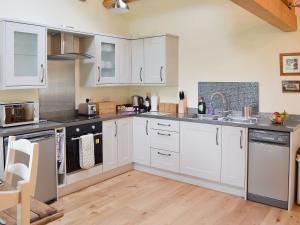 a kitchen with white cabinets and a wooden floor at Brow View Cottage in Ravenstonedale +14 photos