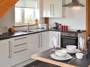 a kitchen with white cabinets and a sink and a table at Gwelfor in Trearddur