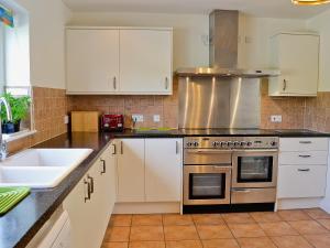 a kitchen with a stove and a sink at Woodbrook Cottage in Bridport