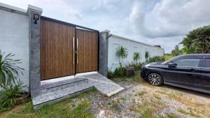 a car parked next to a house with a fence at Bukettree homestay satun in Ban Khok