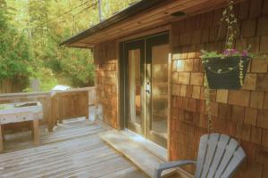 a wooden deck with a chair and a window at Tonquin Beach House - EV Charger, Wood Fireplace, Steps from beach in Tofino