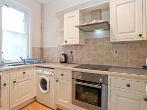 een keuken met witte kasten en een wasmachine en droger bij Bridge End - E1028 in Waxham