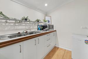 a kitchen with white cabinets and a sink at Tamborine Mountain Lodge in Mount Tamborine
