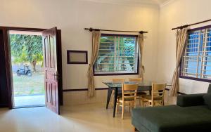 een woonkamer met een tafel en stoelen en een deur bij Ground Zero Martial Arts and Yoga in Phumĭ Réach Born