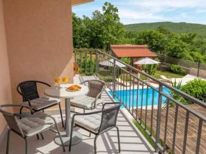 een balkon met een tafel en stoelen en een zwembad bij Prima Natura, Imotski in Kutleše