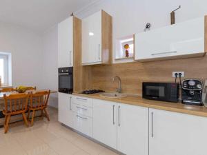 een keuken met witte kasten, een wastafel en een tafel bij Holiday home in Slivno with swimming pool in Slivno