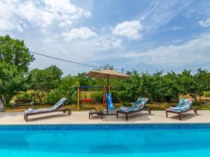 a pool with two chairs and a swing and an umbrella at Villa Mia with pool in Aračići