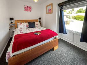 Culver Cottage - Uk48987 في لوي: غرفة نوم بها سرير وبطانية حمراء ونافذة