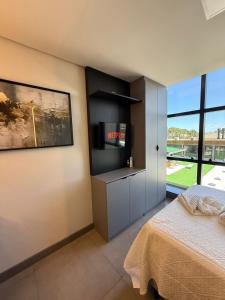 a bedroom with a bed and a large window at Loft em Xangri-Lá com piscina aquecida in Xangri-lá