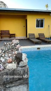 a swimming pool in front of a yellow house at Alojamiento MD in Wanda