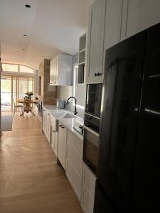 a kitchen with white cabinets and a black refrigerator at Wisemans Ferry Cabin in Wisemans Ferry