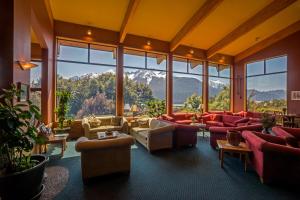a large room with couches and chairs and windows at Wilderness Lodge Arthurs Pass in Arthur's Pass