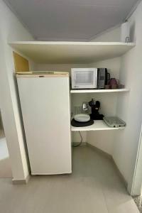 a small kitchen with a white refrigerator and a microwave at Casa Canto de Geribá, 10 min da Praia in Búzios