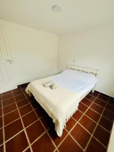a bed in a room with a tiled floor at Casa Canto de Geribá, 10 min da Praia in Búzios +1 photo