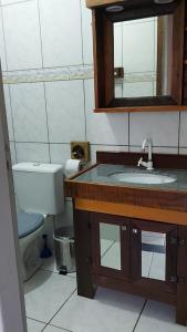 a bathroom with a sink and a toilet and a mirror at Kitinet 06 aconchego, 350 meters from 4 Ilhas in Bombinhas