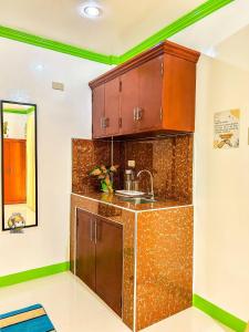 a kitchen with brown cabinets and a sink at Felicitas Guest House- Siargao in General Luna