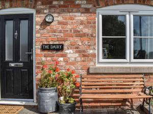 een bakstenen gebouw met een houten bank naast een deur bij The Dairy At Brook House Farm-Uk40631 in Church Minshull +4 foto's