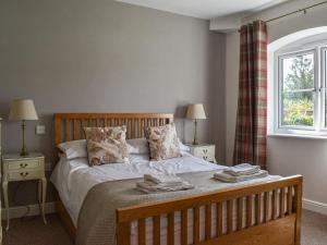 een slaapkamer met een bed met 2 nachtkastjes en een raam bij The Dairy At Brook House Farm-Uk40631 in Church Minshull