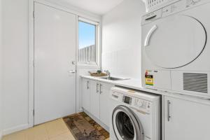 een witte wasruimte met een wasmachine en droger bij Sorrento City Style in Sorrento