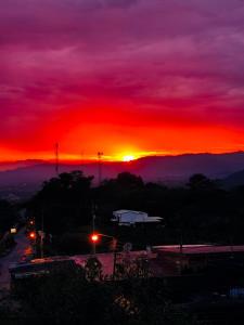 a sunset with the sun setting over a city at Hotel Mirador Mayday Mountain View in Alajuela City